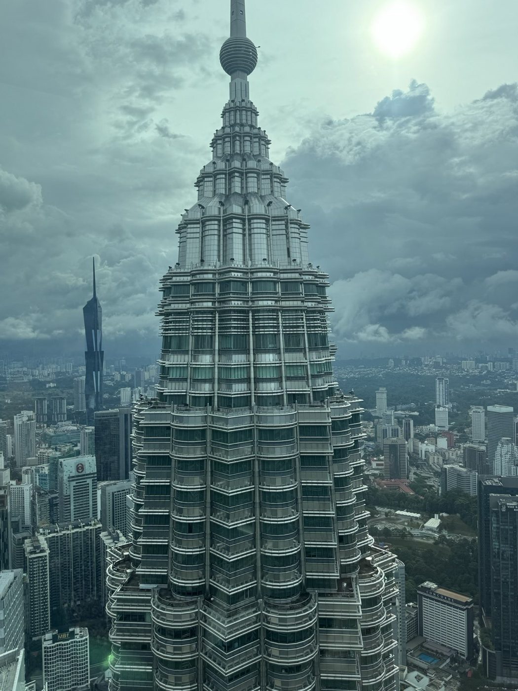 Close-up of a Petronas Tower pinnacle above the Kuala Lumpur skyline